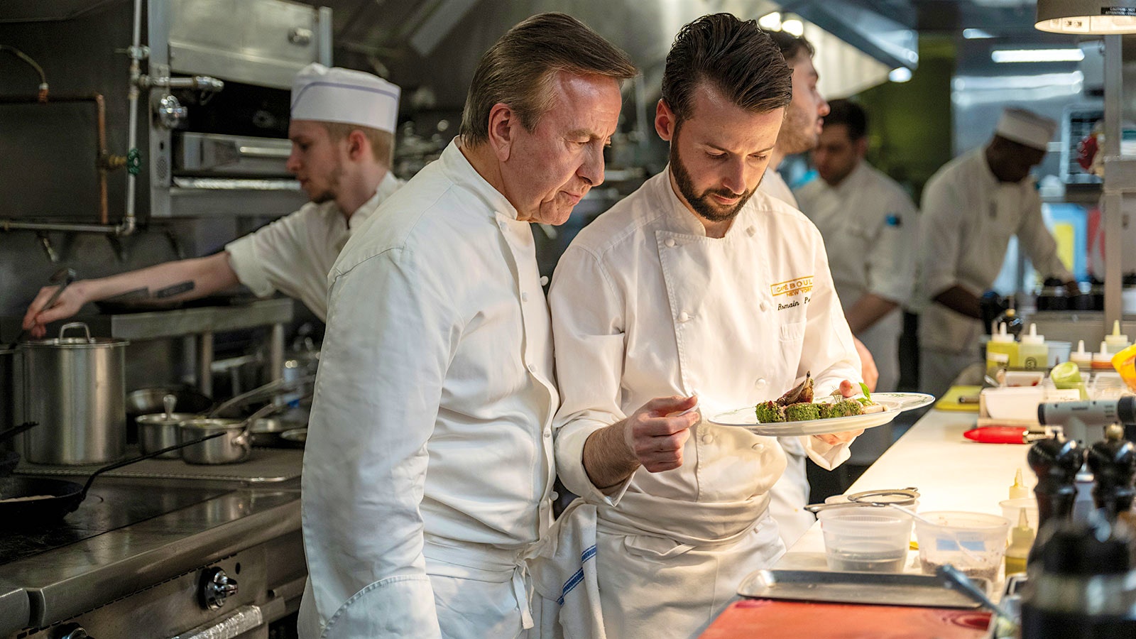 Chef Daniel Boulud perfects orders in the kitchen at the new Café Boulud with executive chef Romain Paumier.